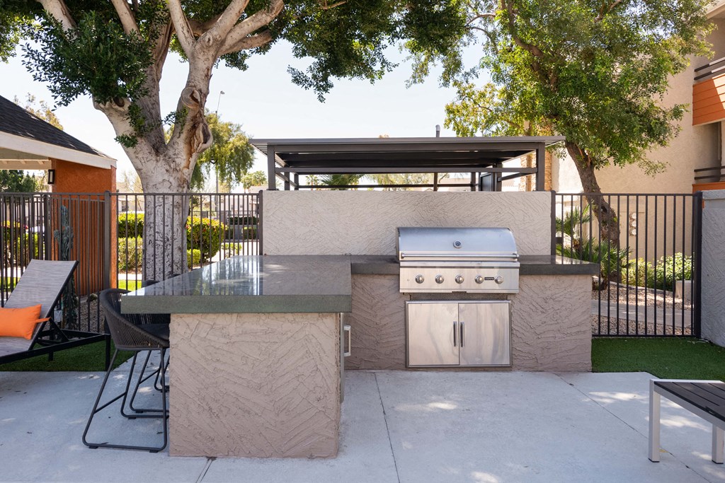 the outdoor kitchen has a grill and a table and chairs