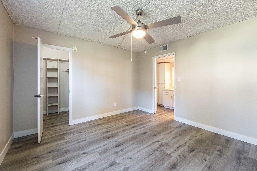 an empty living room with a ceiling fan and a closet