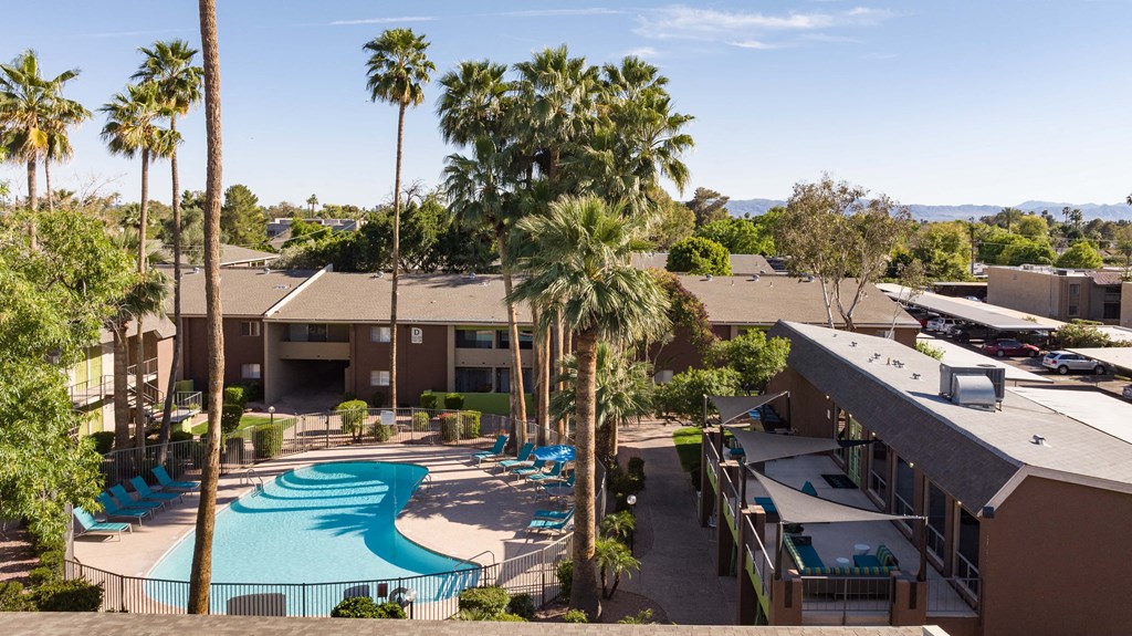 an aerial view of a resort with a swimming pool and palm trees