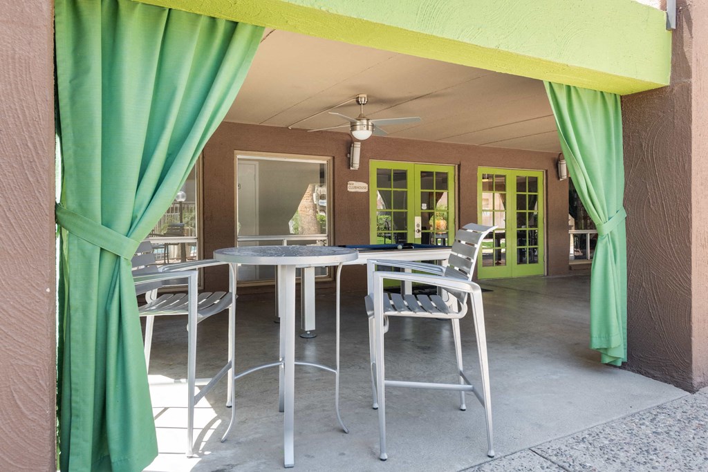 a patio with a table and chairs and a green curtain
