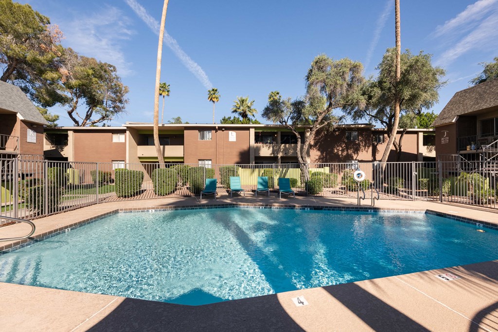 a swimming pool with chairs in front of a building