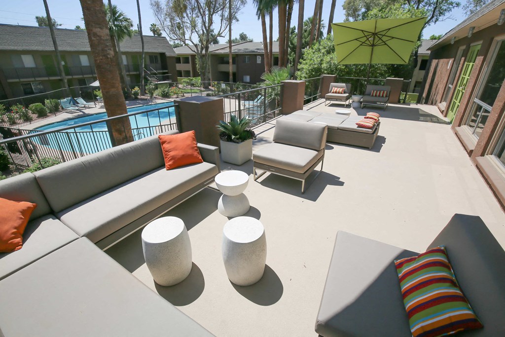 a large patio with couches and tables and a pool