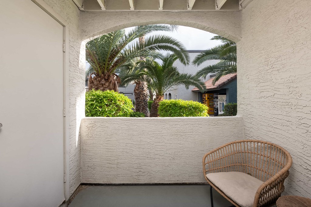 a balcony with a chair and palm trees