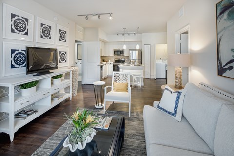 A living room with a white couch and a glass coffee table.