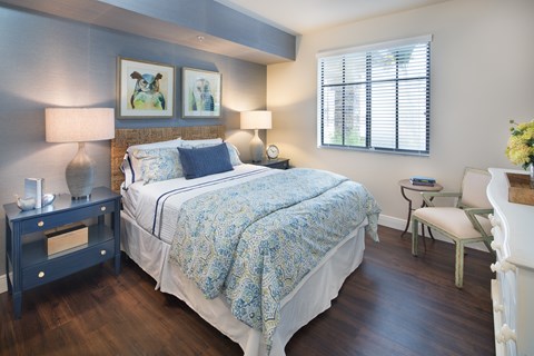 A bedroom with a bed, nightstand, and chair.