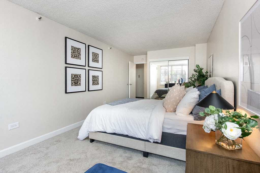 a bedroom with white walls and a bed with white sheets and pillows