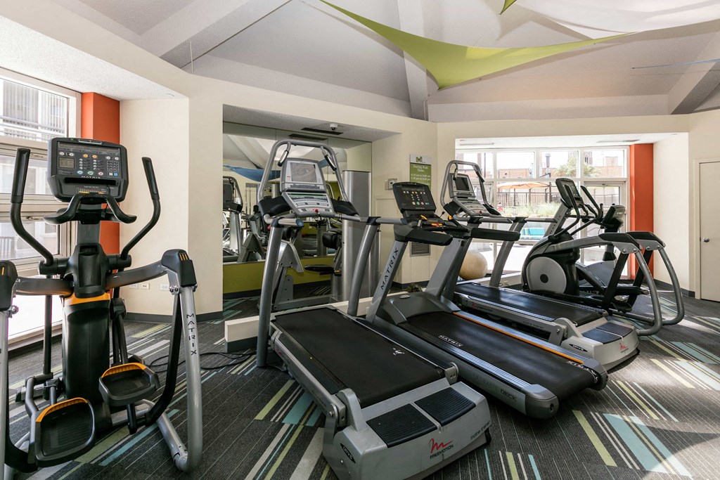 a gym with cardio equipment on the floor and a large window