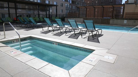 the pool and chaise lounge chairs in the pool area of an apartment building