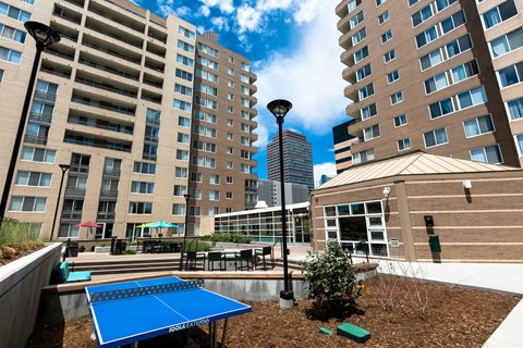 a blue ping pong table is in a courtyard between two tall buildings