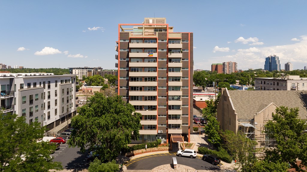 A tall building with a red frame stands in the middle of a city.