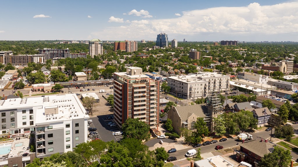 A cityscape with buildings and trees under a blue sky.