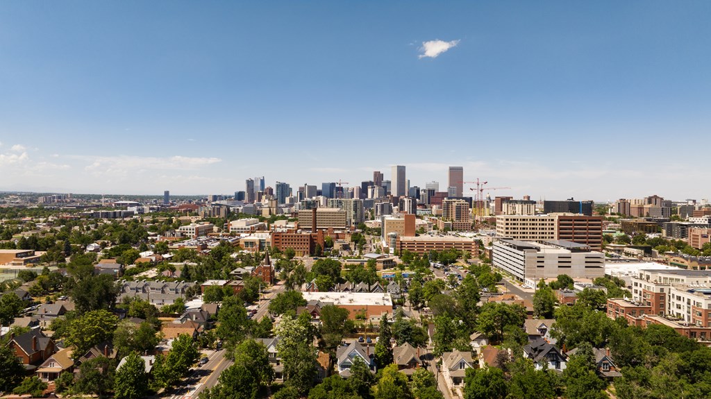 A cityscape with a mix of residential and commercial buildings under a clear sky.