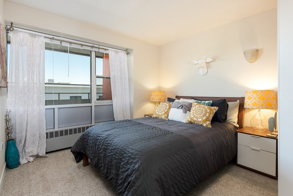 A bedroom with a large bed and a window with curtains.
