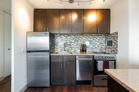 A modern kitchen with dark wood cabinets and stainless steel appliances.