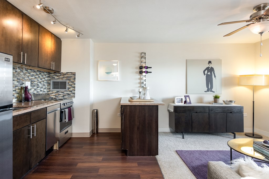 A modern kitchen with dark wood floors and a marble backsplash.