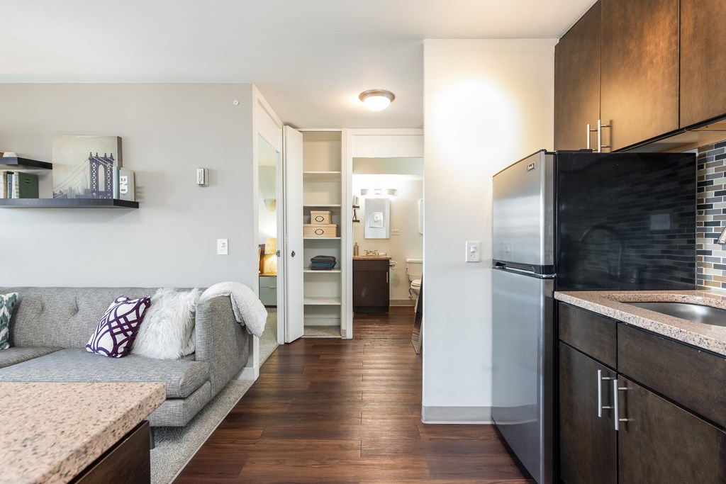 A kitchen with a refrigerator, a couch, and a counter.