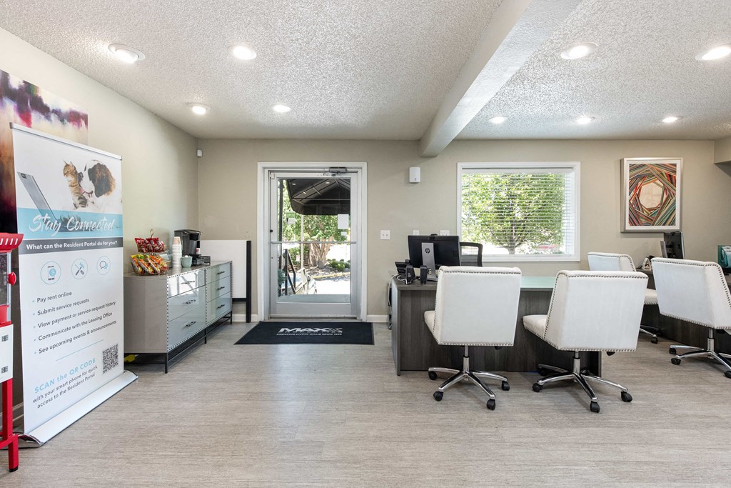 a break room with white chairs and a desk and a doorway