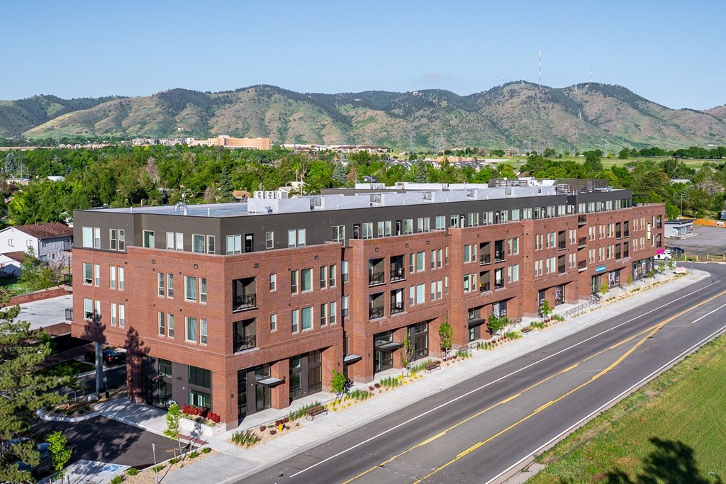 A large red brick building with a mountain in the background.