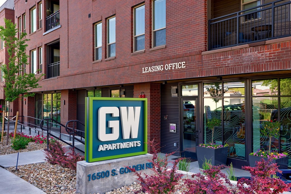 A red brick building with a green and white sign that says GW Apartments.