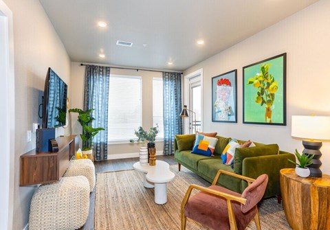 A living room with a green couch, a white coffee table, and a painting on the wall.