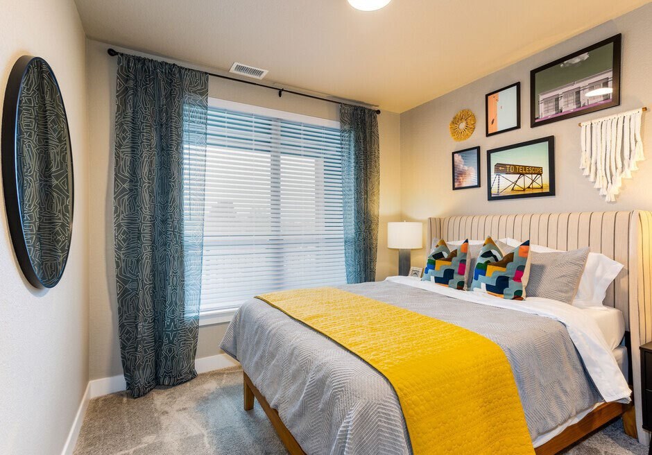 A bedroom with a bed, a mirror, a chandelier, and pictures on the wall.