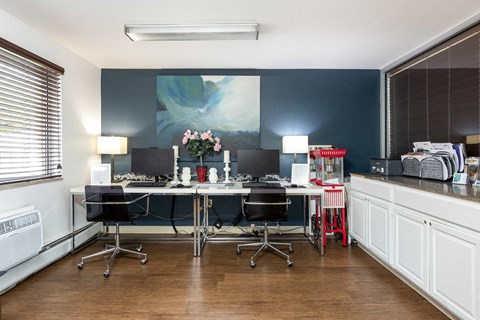 an office with desks and chairs and a painting on the wall