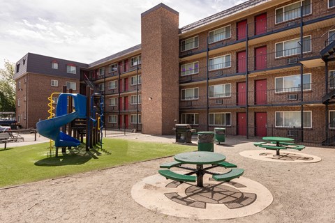 a playground in the courtyard of an apartment building with a blue slide