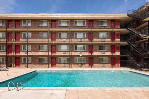 the pool is in front of a red brick building with a swimming pool