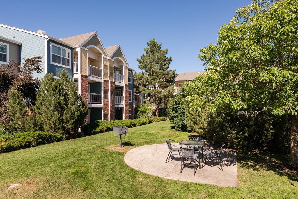 a patio with a table and chairs in front of an apartment building