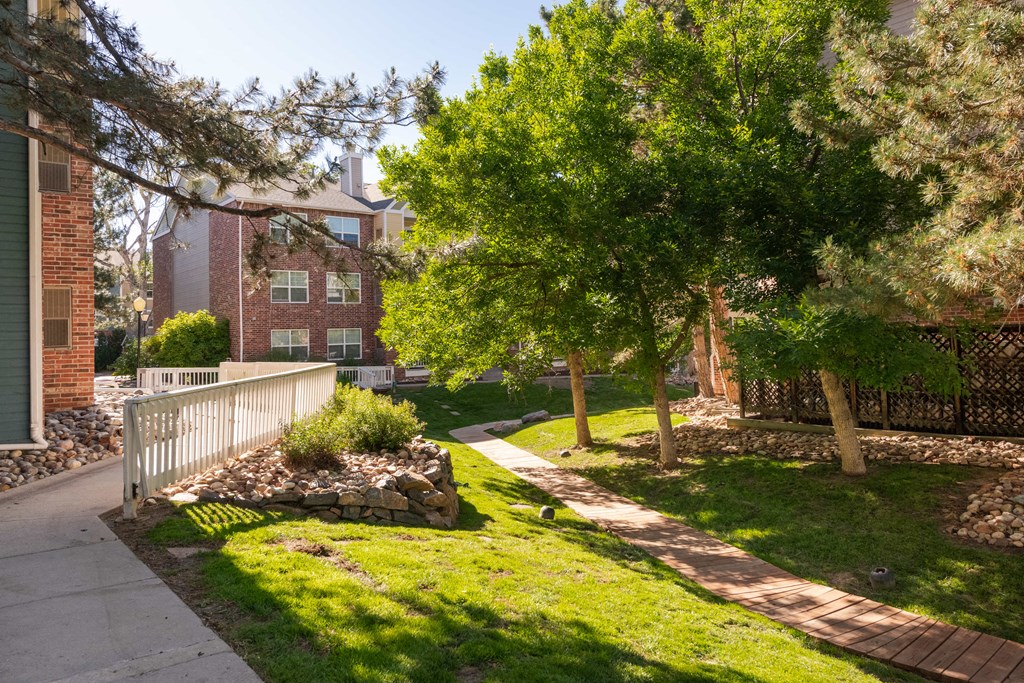 a sidewalk and trees in front of a brick building