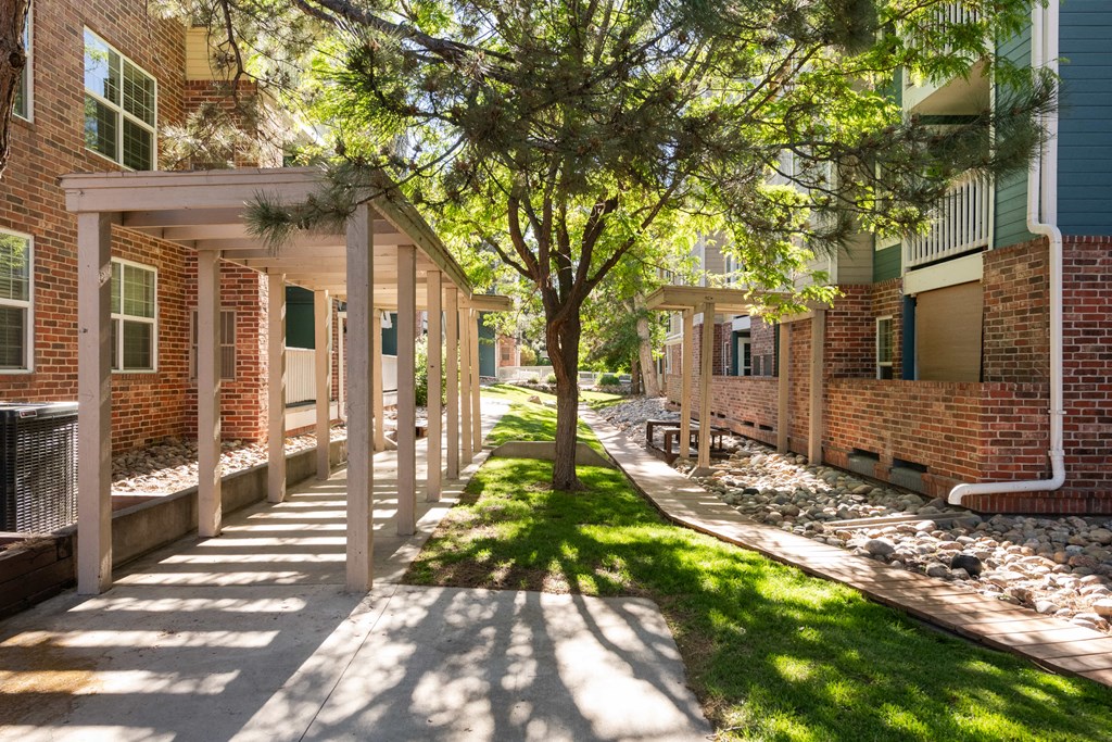 a sidewalk in front of a brick building with trees