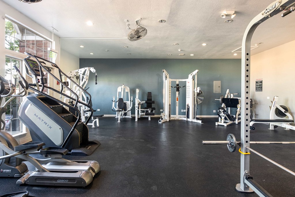 a gym with cardio equipment and weights on the floor