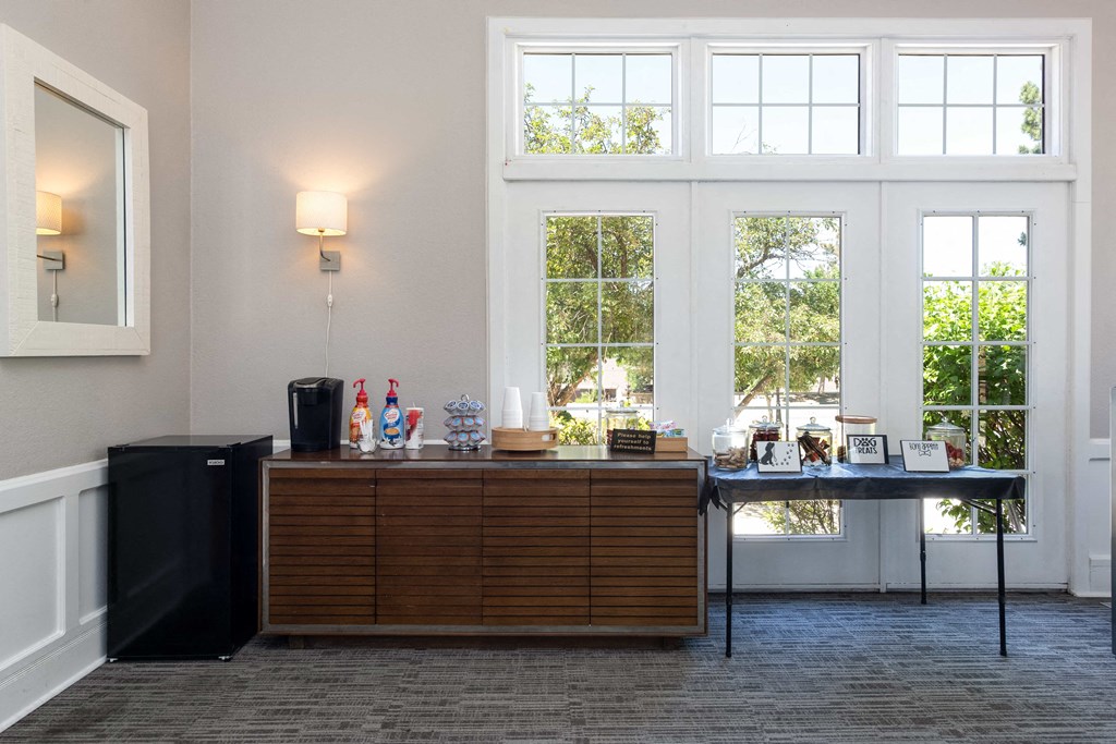 a bar in a room with large windows and a table with drinks on it
