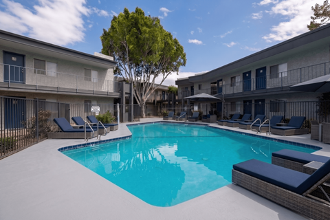 A swimming pool surrounded by lounge chairs and trees.