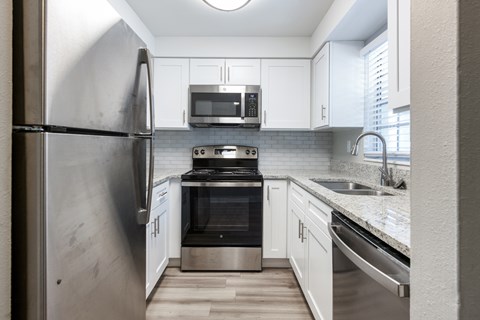A modern kitchen with a stainless steel refrigerator and white cabinets.