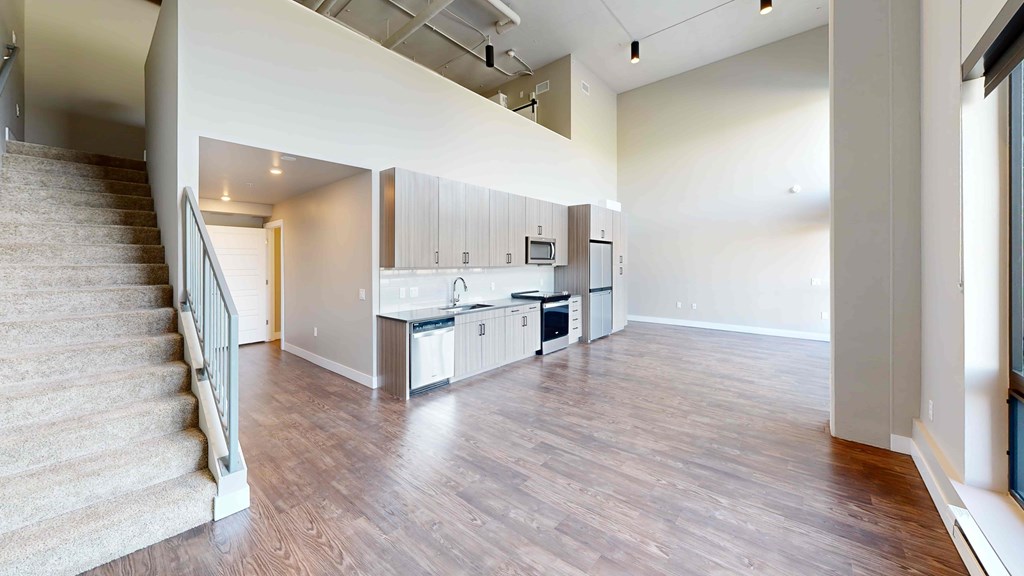 A spacious living room with a staircase on the left side.
