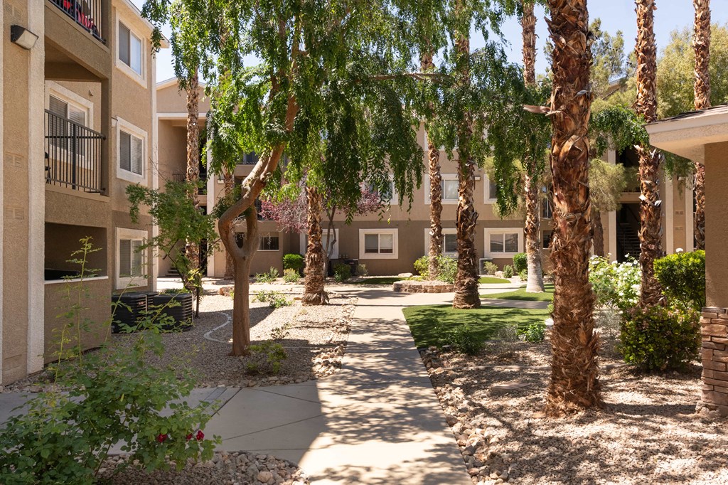 a courtyard with trees and a sidewalk in front of an apartment building
