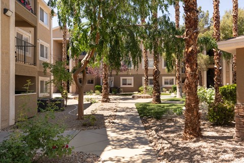 a courtyard with trees and a sidewalk in front of an apartment building