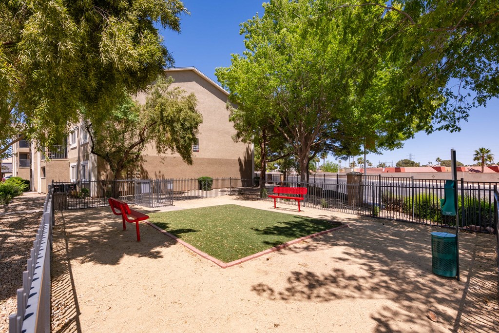 a dog park with grass and benches in front of a building