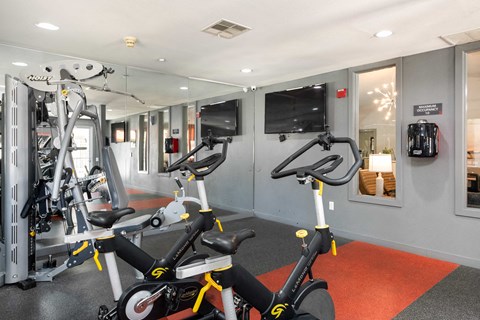 a gym with exercise bikes and a tv in the wall