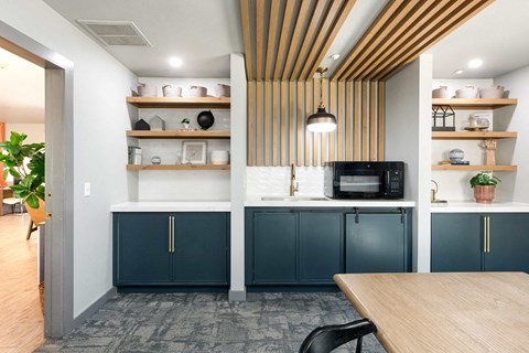 a kitchen with blue cabinets and a table and a microwave