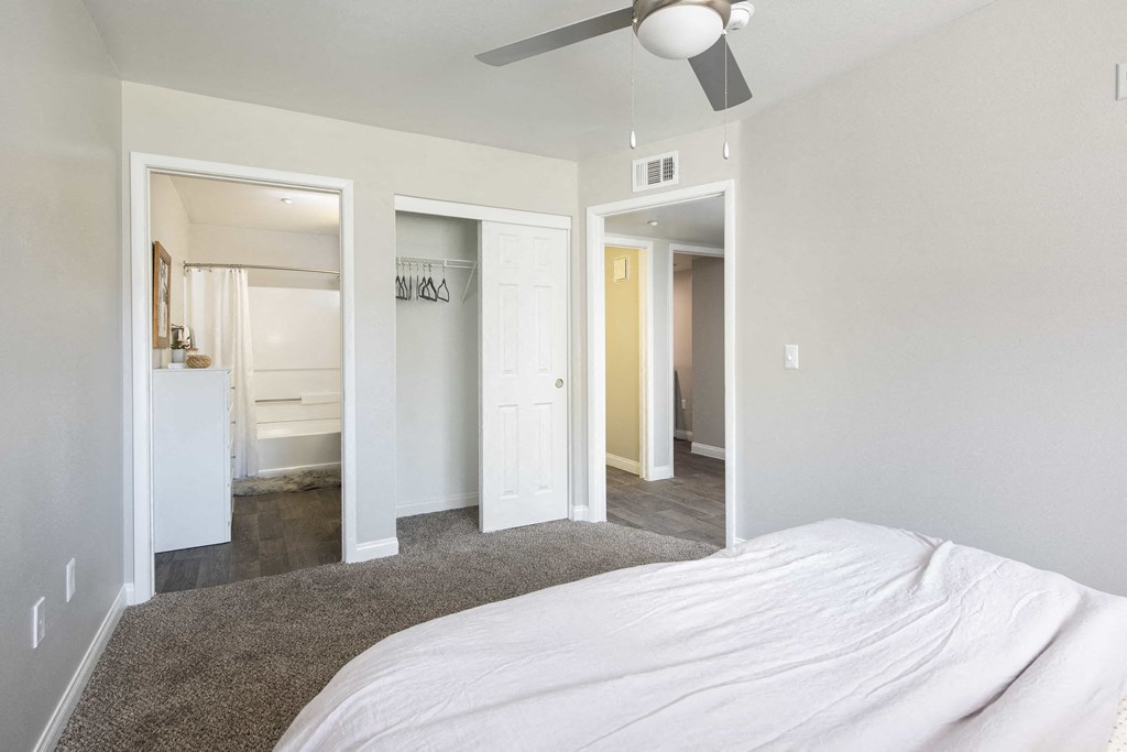 a bedroom with a white bed and a ceiling fan