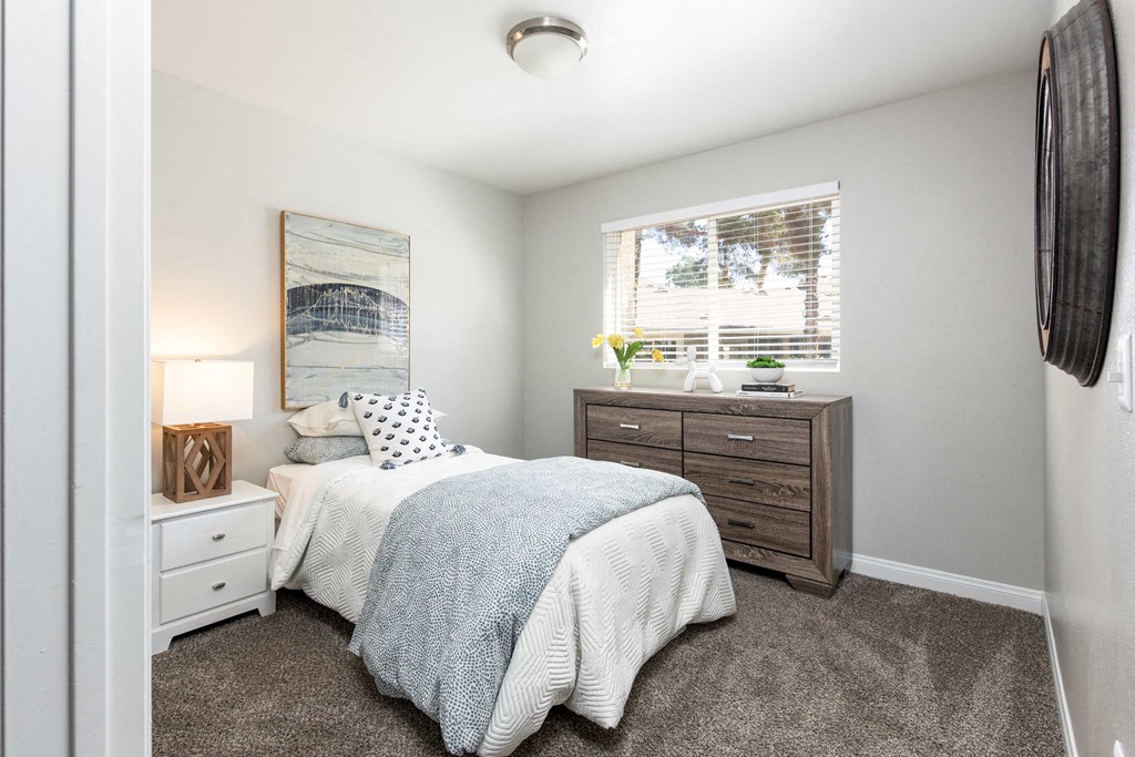 a bedroom with a bed and a dresser and a window