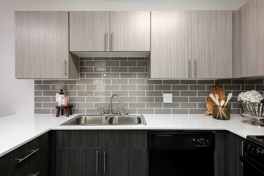 a kitchen with a sink and gray tiles