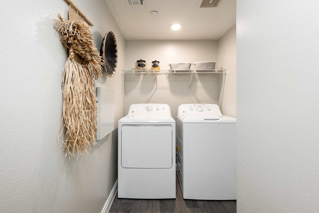 a washer and dryer in a laundry room with a plant on the wall