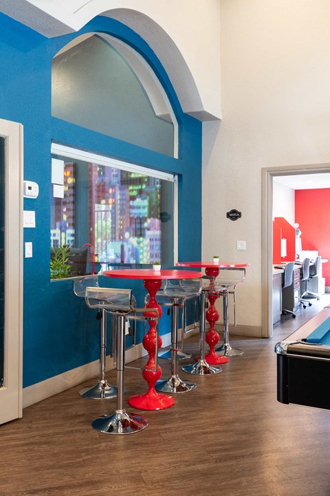 a bar with red chairs and a blue wall with a window