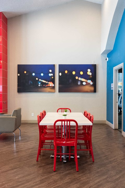 a dining room with a table and chairs and two paintings on the wall