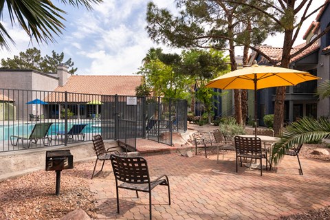 a patio with chairs and an umbrella next to a swimming pool
