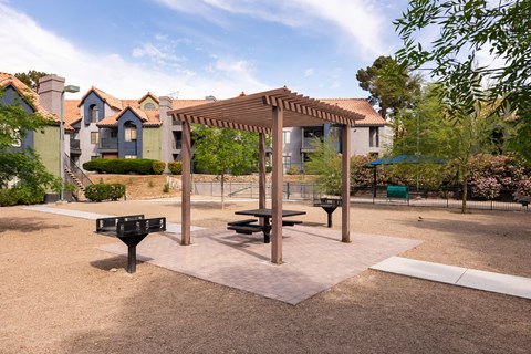 a picnic area with a picnic table and benches in front of apartment buildings