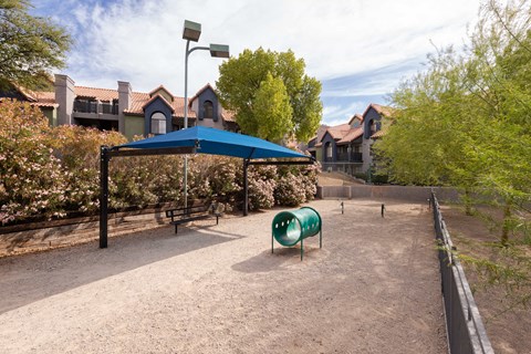 a playground with a blue tent and a green chair     and houses